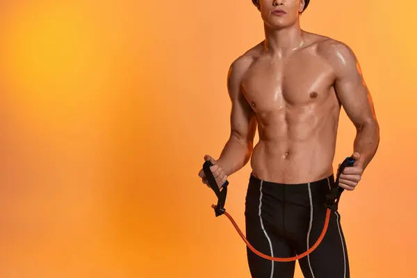 Recortado vista de joven deportivo posando en topless sobre fondo gris y entrenamiento con expansor de fitness - foto de stock