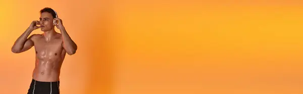 Young sporty man posing topless while wearing headphones and looking away on vivid backdrop, banner — Stock Photo