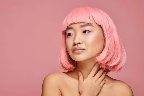 Alluring asian woman with pink hair looking to side and touching her neck on vibrant background — Stock Photo