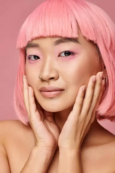 Retrato de encantadora chica asiática con piercing en la nariz tocando la mejilla con las manos sobre un fondo vibrante - foto de stock