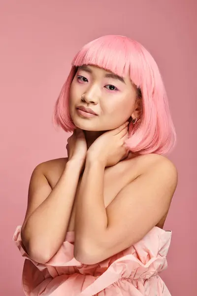 Retrato de mujer encantadora con cabello rosa y maquillaje tocando el cuello con las manos sobre un fondo vibrante - foto de stock