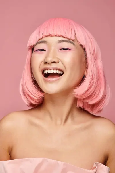 Pretty young woman with pink hair and makeup laughing against vibrant background — Stock Photo