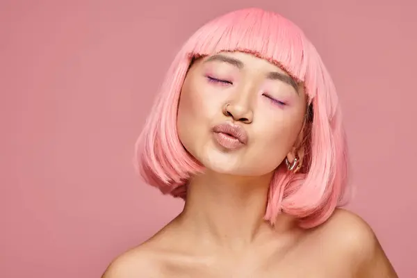 Красивая молодая женщина с розовыми волосами и макияжем воздуха поцелуи с закрытыми глазами на ярком фоне — стоковое фото