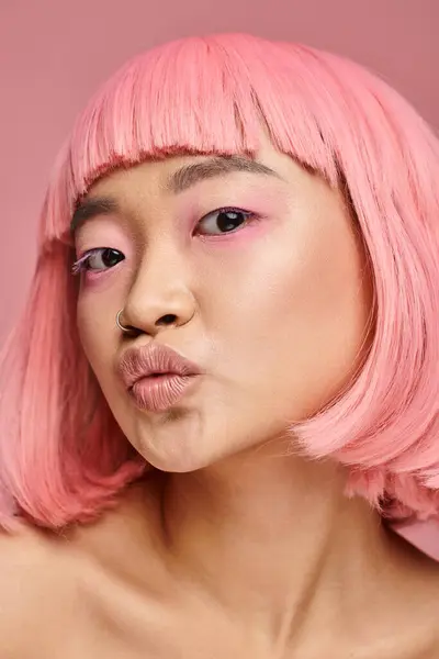 Verspielte und charmante junge Frau mit rosa Haaren und Make-up küsst vor lebendigem Hintergrund — Stockfoto