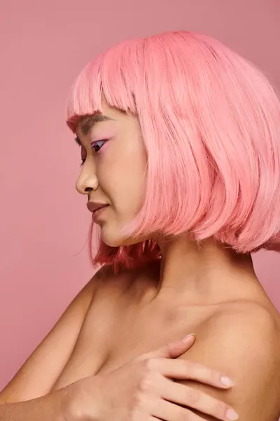 Профиль привлекательной азиатской молодой женщины с розовыми волосами и макияжем на ярком фоне — стоковое фото