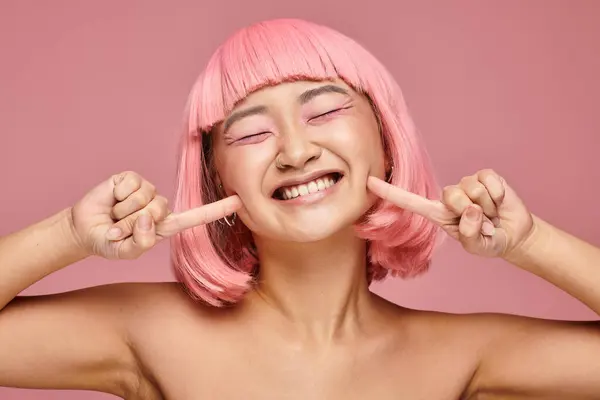 Mignon asiatique jeune fille avec rose cheveux et maquillage souriant largement sur fond vibrant — Photo de stock