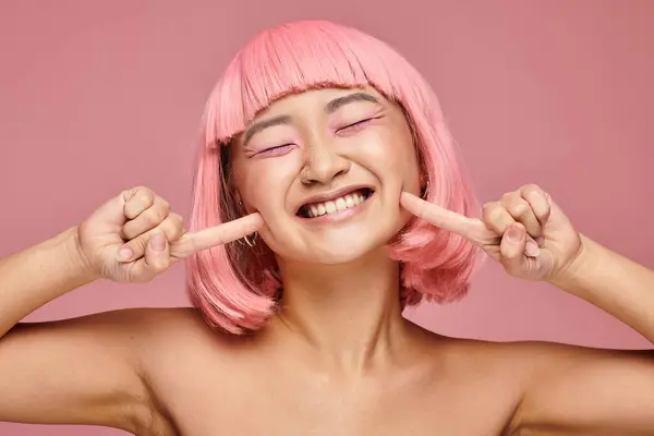 Cute asian young girl with pink hair and makeup smiling broadly against vibrant background — Stock Photo