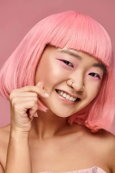 Carino asiatico ragazza con naso piercing mostrando cuore segno e sorridente ampiamente in vibrante sfondo — Foto stock