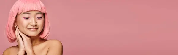 Горизонтальный снимок милой азиатской женщины с розовыми волосами, смотрящей вниз с руками на ярком фоне — стоковое фото