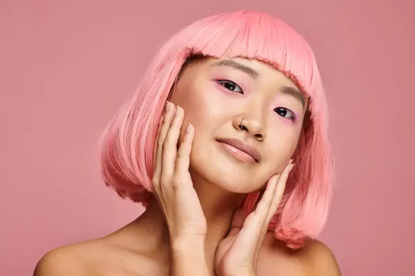 Attraktive asiatische Frau mit rosa Haaren posiert mit Händen vor lebendigem Hintergrund — Stockfoto