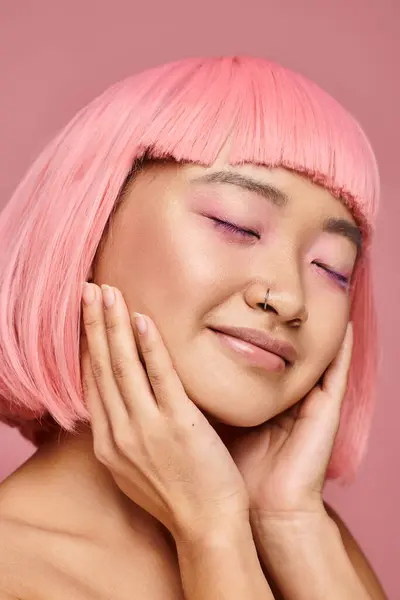Очаровательная женщина с розовыми волосами закрывая глаза и позируя руками на ярком фоне — стоковое фото