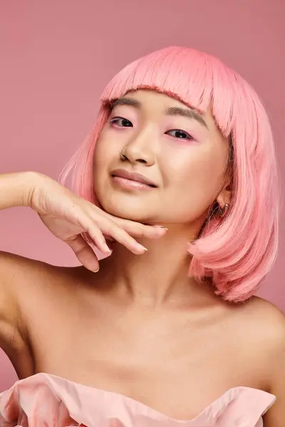 Alluring asian woman in 20s with pink hair touching to chin with hand on vibrant background — Stock Photo