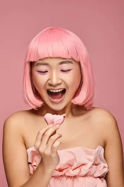 Beautiful asian young woman with pink hair surprised of mochi against vibrant background — Stock Photo