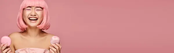 Bannière de mignon asiatique femme avec des cheveux roses heureux rire et tenant des bonbons sur fond vibrant — Photo de stock