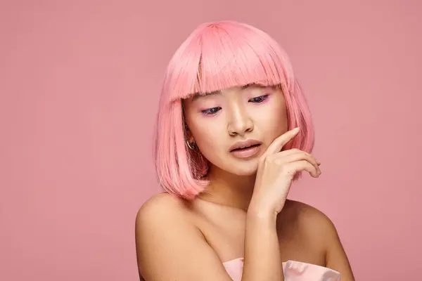 Verführerische asiatische junge Frau mit rosafarbenen Haaren, die bis zum Kinn reichen und nach unten in den lebendigen Hintergrund schauen — Stockfoto