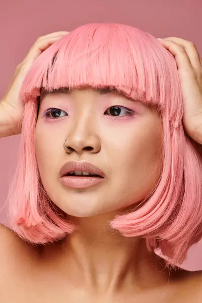 Close up of asian woman with pink hair and piercing posing with hands on head on vibrant background — Stock Photo