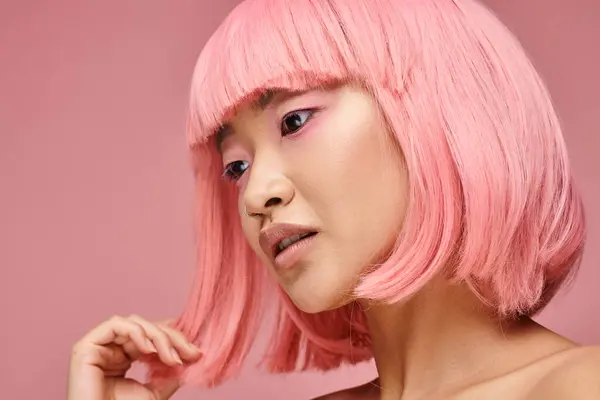 Affascinante asiatico donna con naso piercing toccare a capelli e guardando a giù su vibrante sfondo — Foto stock