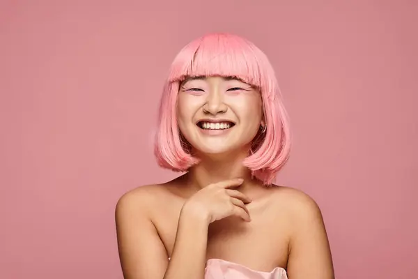 Happy asian young woman with pink hair and makeup laughing against vibrant background — Stock Photo