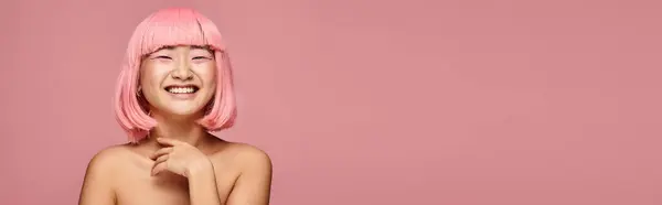 Horizontal tiro de precioso asiático chica con rosa pelo y maquillaje riendo contra vibrante fondo - foto de stock