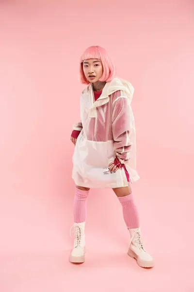 Confiante femme asiatique dans sa vingtaine avec des cheveux roses dans une tenue élégante posant sur fond vibrant — Photo de stock