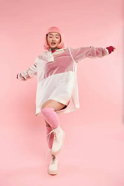 Atractivo asiático mujer en 20s con rosa pelo en elegante traje posando contra vibrante fondo - foto de stock
