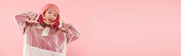 Горизонтальный снимок азиатской молодой женщины с розовыми волосами, позирующей с руками на голове на ярком фоне — стоковое фото