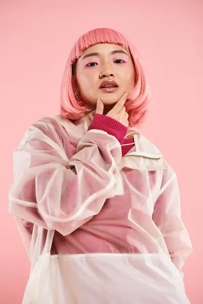Красивая азиатская женщина в 20 лет с розовыми волосами и макияжем касаясь подбородка на ярком фоне — стоковое фото