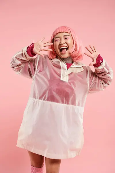 Gai asiatique femme avec rose cheveux et maquillage heureux rire avec les mains sur fond vibrant — Photo de stock