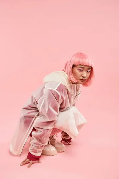 Милая азиатская женщина в 20 лет с розовыми волосами в стильном наряде присел на живом фоне — стоковое фото