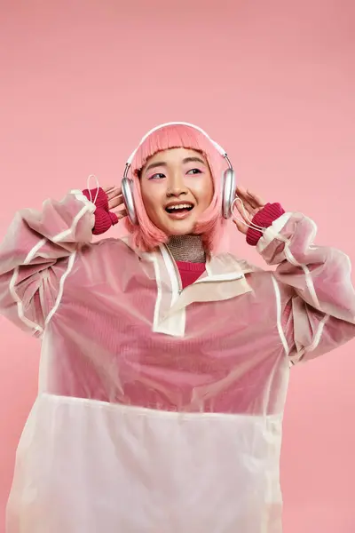 Mignon asiatique jeune fille avec rose cheveux écoute musique avec écouteurs sur fond vibrant — Photo de stock