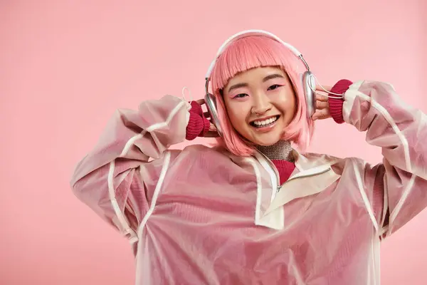 Belle asiatique fille dans les années 20 avec rose cheveux écouter de la musique avec écouteurs sur fond vibrant — Photo de stock