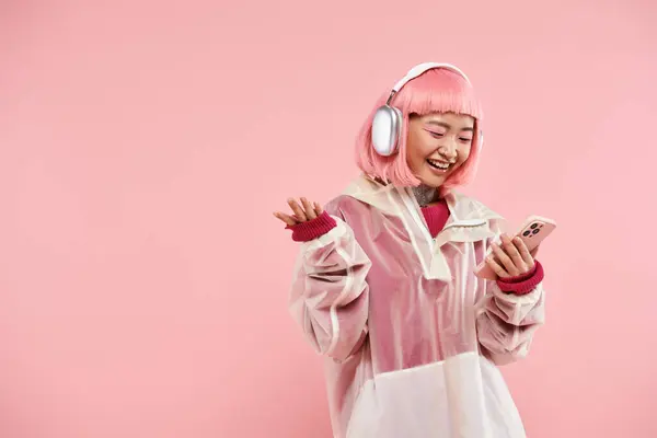 Cute asian woman in 20s with pink hair in headphones browsing social media in vibrant background — Stock Photo