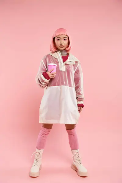 Charming asian young woman in pink stylish outfit posing with cup of coffee on vibrant background — Stock Photo