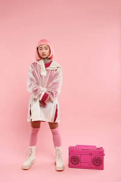 Confiado asiático joven mujer con rosa pelo posando con boombox en vibrante fondo - foto de stock