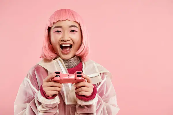 Приваблива азіатська дівчина в стильному вбранні щаслива гра на джойстику на яскравому фоні — стокове фото