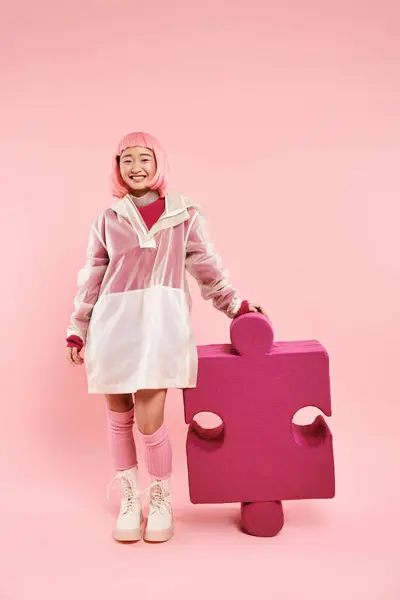 Bonito asiático jovem menina com rosa cabelo posando com grande quebra-cabeça no vibrante fundo — Fotografia de Stock