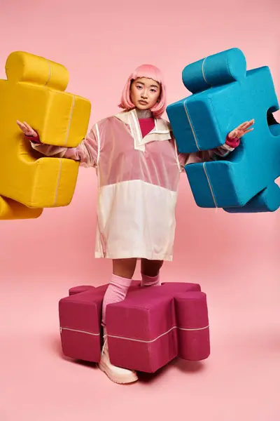 Atractiva joven con el pelo rosa posando con grandes puzzles sobre un fondo vibrante — Stock Photo