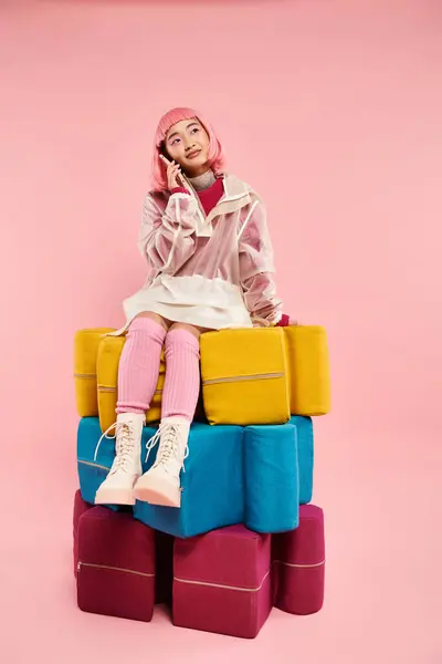 Cute girl with pink hair sitting on larges puzzles and calling on smartphone in vibrant background — Stock Photo