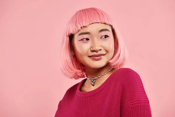 Atractiva chica asiática en 20s con collar de perlas, pelo rosa y maquillaje contra fondo vibrante - foto de stock