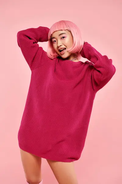 Cute asian young woman with pink hair and makeup in big sweater against vibrant background — Stock Photo
