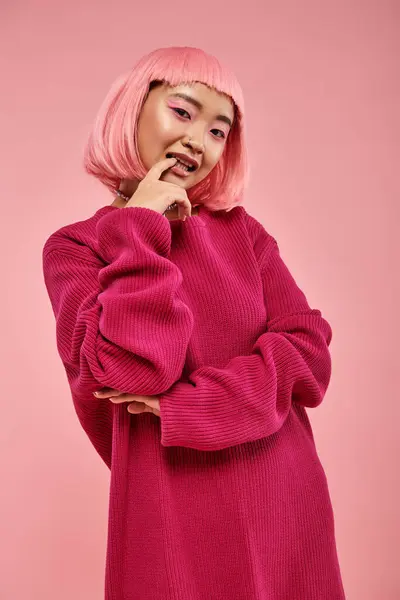 Jovem bonita com cabelo rosa posando e mordendo unha contra fundo vibrante — Fotografia de Stock