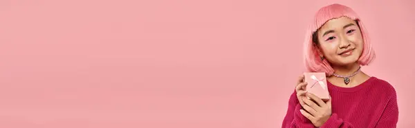 Horizontal view of attractive asian woman posing with pink gift against vibrant background — Stock Photo
