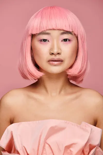 Attraente asiatico giovane donna con rosa capelli e trucco cercando per fotocamera su vibrante sfondo — Foto stock