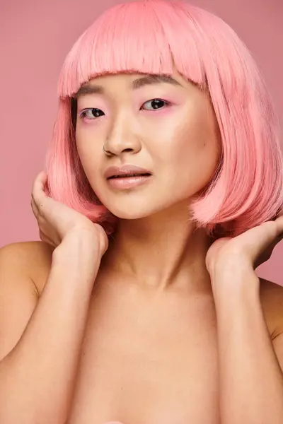 Lovely asian young girl with pink hair fixing hairstyle against vibrant background — Stock Photo