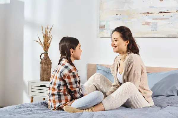 A moment of serenity as a mother and daughter sit together on a bed, enjoying some quality time together. — Stock Photo