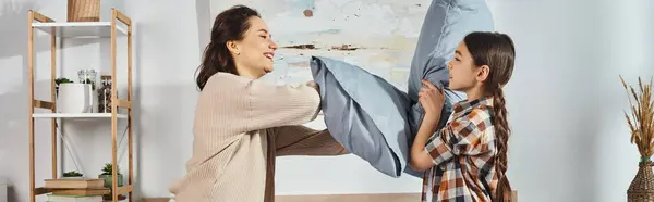 Une mère et sa fille jouant joyeusement ensemble sur le lit, tissant des liens et créant des souvenirs à la maison. — Photo de stock