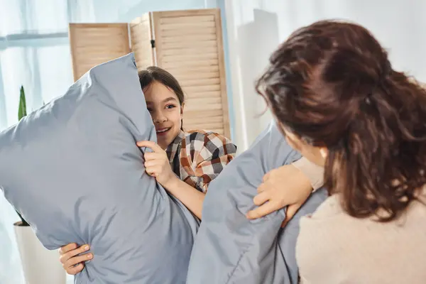 Uma menina segura um travesseiro enquanto a mãe olha para ela, compartilhando um momento terno de conforto e apoio em casa.. — Fotografia de Stock