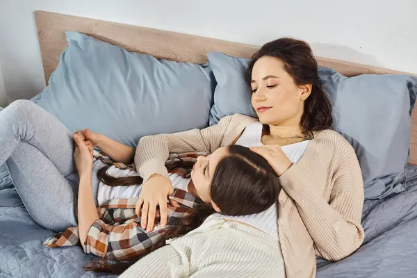 Une mère et sa fille se détendent ensemble sur un lit douillet, partageant un temps précieux de qualité dans un cadre calme et paisible. — Photo de stock