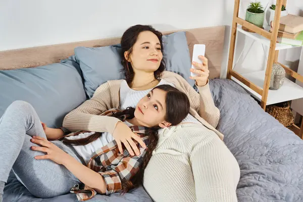 Une mère et sa fille sont tranquillement allongées sur un lit, profitant de moments de qualité ensemble dans un cadre confortable à la maison. — Photo de stock