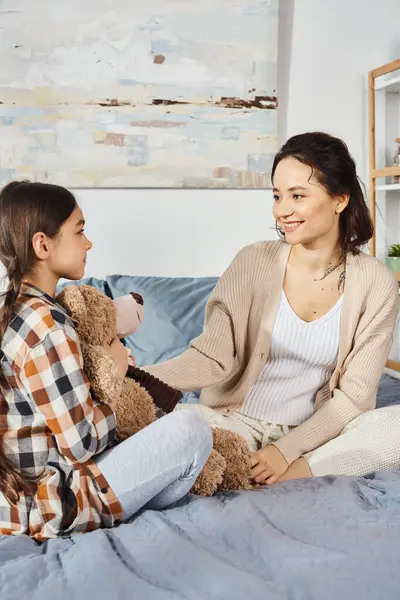 Eine Frau sitzt auf einem Bett neben einem kleinen Mädchen und teilt einen besonderen Moment der Liebe und Verbundenheit zu Hause. — Stockfoto